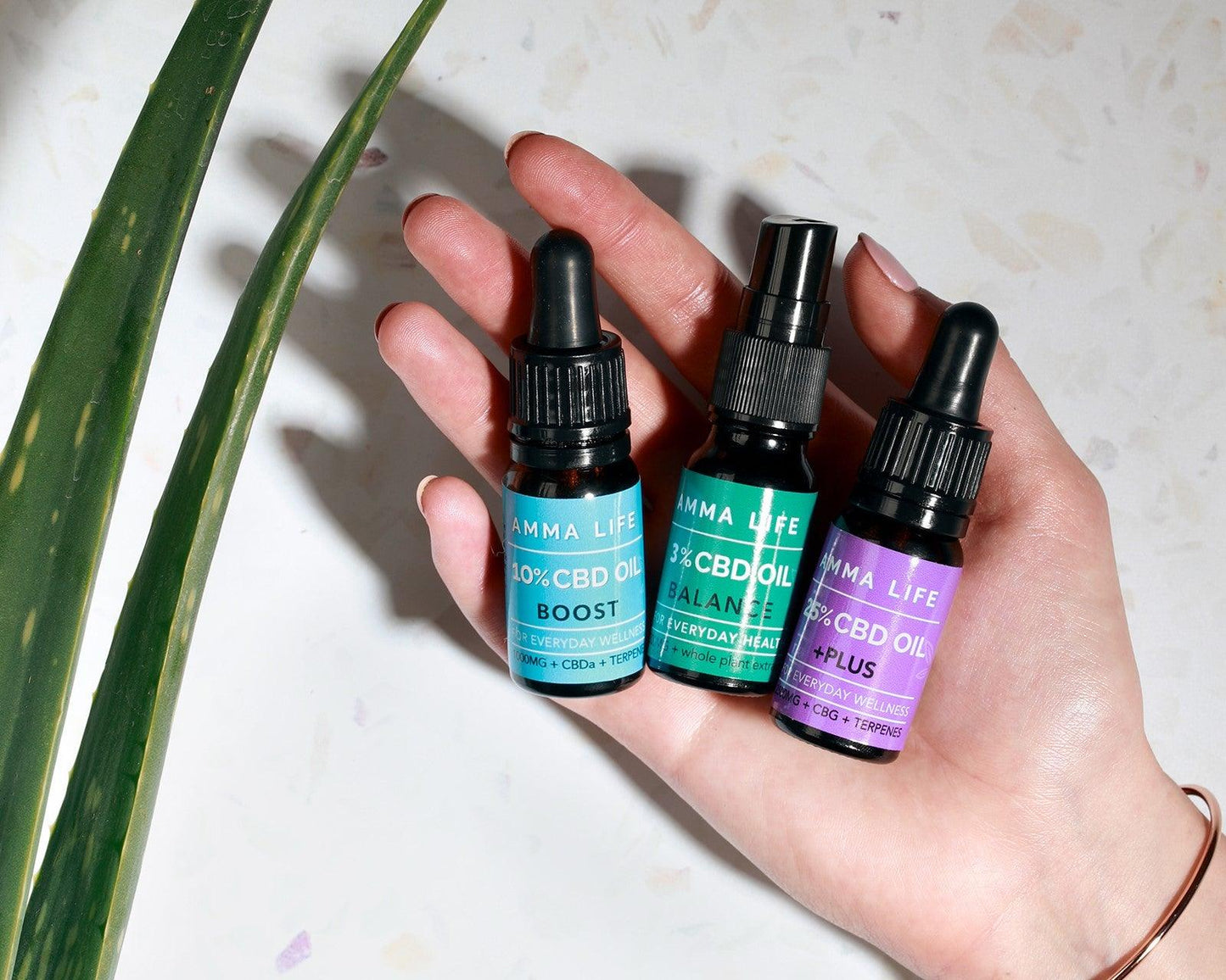 Amma Life CBD oils (3 bottles) in palm of female hand.