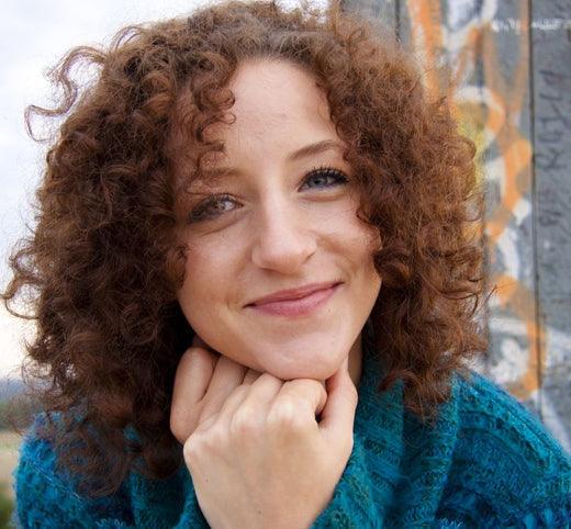Close up of happy woman with curly auburn coloured hair.